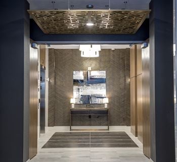 A view of the elevator lobby of a building with a blue and gold elevator lobby